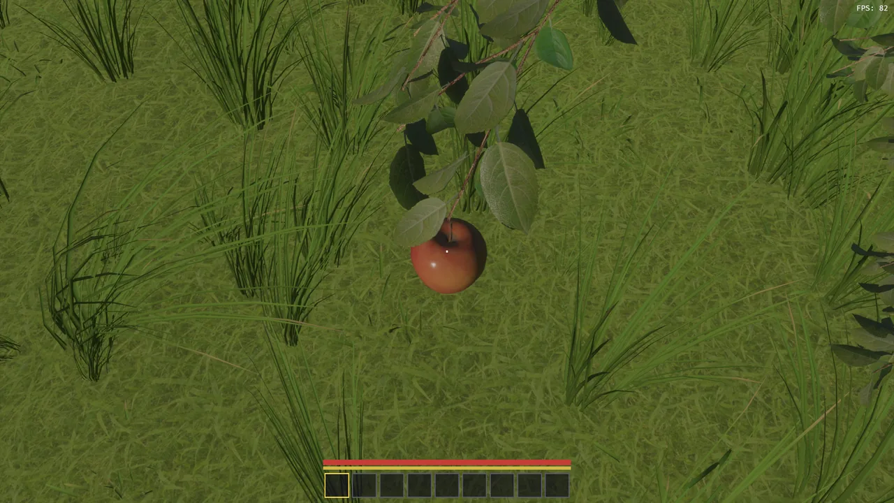 A single red apple hanging from a branch over the grass.