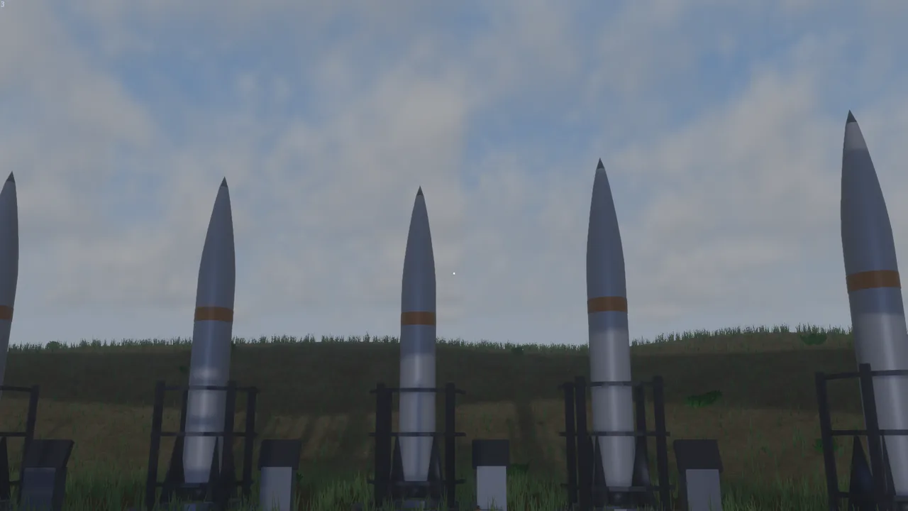 A row of missiles standing on their launch cradles in a grassy field under an overcast sky.